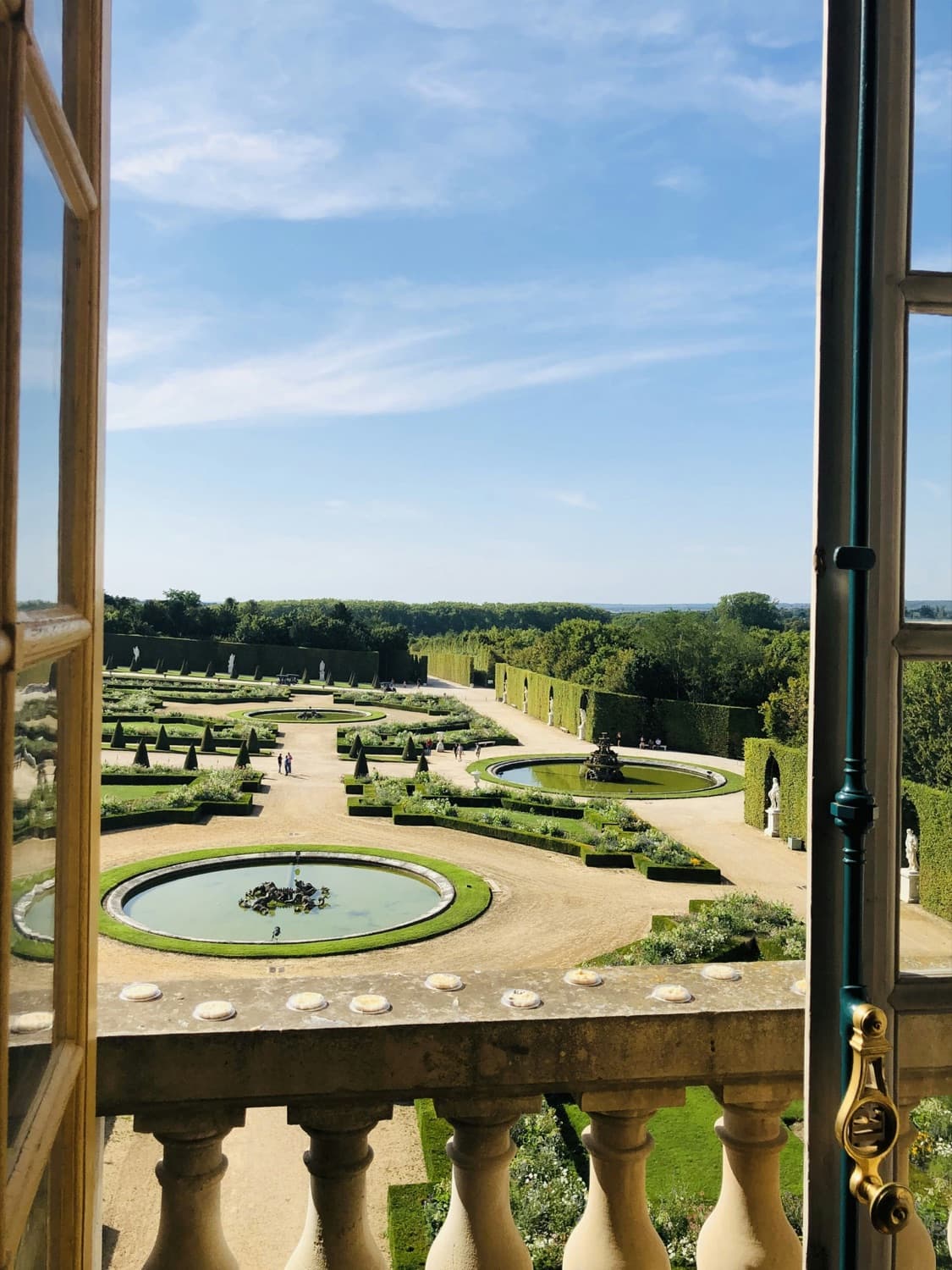 A formal garden seen through tall open balcony doors