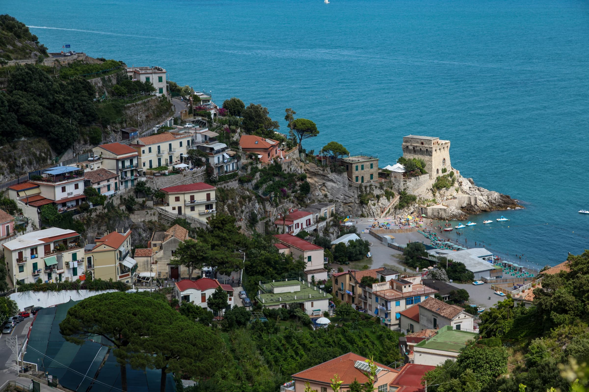 A pastel cliffside village on the Amalfi Coast, above a small cove with a stone watchtower
